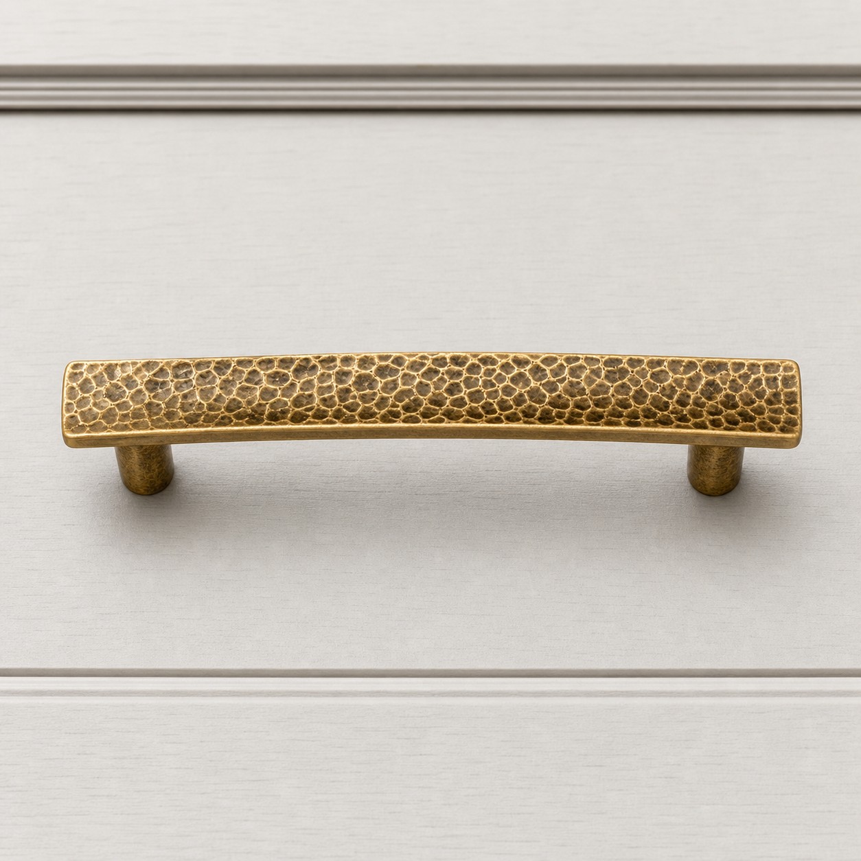 Hammered brass cabinet pull on white cabinet drawer